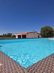 a blue swimming pool with a house in the background at pura natura Alghero in Alghero