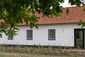 a white house with a red roof at Gastenverblijf Begheynhof - your perfect escape in Biervliet