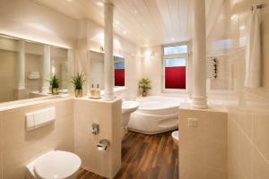 a bathroom with a tub and a toilet and a sink at Hotel Jensen in Lübeck