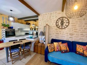 a living room with a blue couch and a kitchen at Domaine Ô Clair de Lune - Chambres d'Hôtes et Gîtes à Sarlat - Accès Cité Médiévale 5 minutes à pied - Parking - SPA & Massages en option - Piscine de saison in Sarlat-la-Canéda