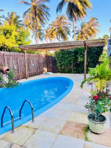 a swimming pool in a yard with a fence and palm trees at Recanto do cajueiro in Flecheiras
