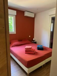 a bedroom with a bed with red sheets and towels on it at Bidart, maisonnette sur les Pyrénées in Bidart