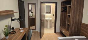a room with a desk and a bathroom with a sink at Drei Schweizer Hotel in Neuwied
