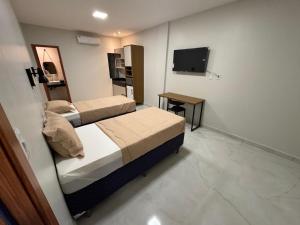 a small room with two beds and a television at Loft Hage in Belém