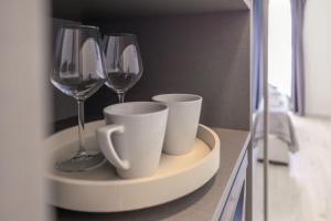 three wine glasses and cups on a shelf in a bathroom at Apartments Marin in Podstrana