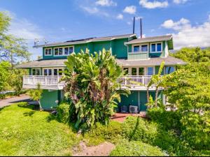 a green house with a palm tree in front of it at Kona Kai Ocean View Suite in Kailua-Kona