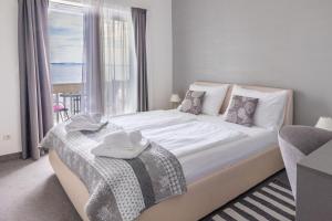 a bedroom with a large white bed with a window at Apartments Marin in Podstrana