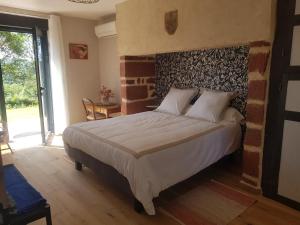 a bedroom with a bed with a brick wall at Maison d'hôtes en grès rouge in Lanteuil