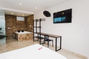 a bedroom with a desk and a bathroom with a tub at Hotel El Descanso in Fusagasuga