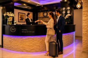 a woman shaking hands with a man at a hotel reception counter at Hotel Beograd Struga in Struga