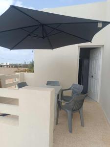 a black umbrella over a table and chairs on a patio at Authentic, quiet and spacious house in El Guecheïne +2 photos