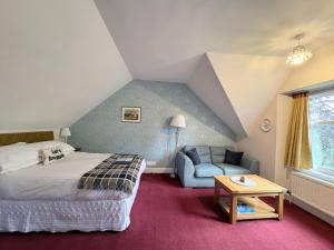 a bedroom with a bed and a chair and a table at Glenan Lodge Self Catering in Tomatin