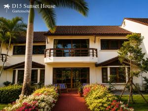 a house with a palm tree and flowers in front of it at Oceanside Place in Rayong