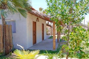 a small white house with a door and some trees at Pousada vila jaguar in Tutóia