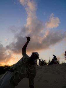 a man standing in the sand with his arm in the air at Pousada vila jaguar in Tutóia