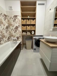 a bathroom with a tub and a sink and a washing machine at Apartmán pod Rovencom in Nové Mesto nad Váhom
