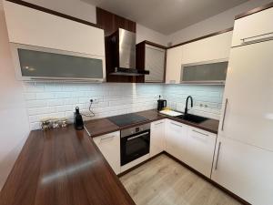 a kitchen with white cabinets and wooden floors at Apartmán pod Rovencom in Nové Mesto nad Váhom