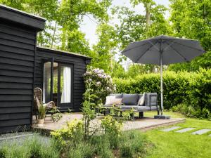 a black shed with a couch and an umbrella at Scandinavian Forest Cabin in Twente in Markelo