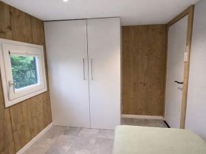 a bedroom with a white cabinet and a window at Scandinavian Forest Cabin in Twente in Markelo