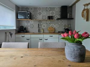 a kitchen with a wooden table with a vase of flowers at Scandinavian Forest Cabin in Twente in Markelo