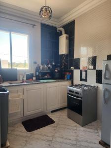 a kitchen with white cabinets and a stove top oven at F3 entre nature et calme in Raʼs al Jabal