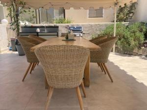 a wooden table with wicker chairs on a patio at La villa des Carriers - maison avec piscine, 10 min mer in Roquefort-les-Pins
