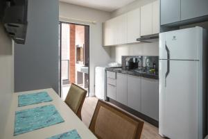 a kitchen with a white refrigerator and a table with chairs at Villa Francione in Bombinhas
