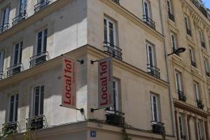 a building with two red signs on the side of it at Hotel Local 101 Beaurepaire in Paris
