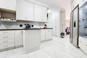 a large white kitchen with white cabinets and appliances at Magic garden in Vereeniging