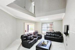 a living room with two leather couches and a table at Magic garden in Vereeniging