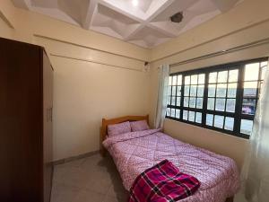 a bedroom with a bed with a pink blanket and a window at Arabella Homes in Maralal