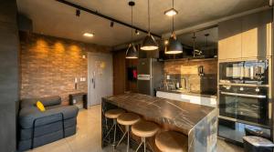 a kitchen with a bar with stools and a couch at Vista Ampla e Estilo Industrial nesse Lindo Loft in Campo Grande