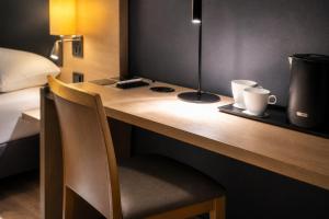 a desk with a lamp and two cups on it at Hotel MIRAGE Düsseldorf-Neuss in Neuss
