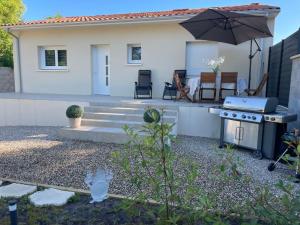 a backyard with a grill and an umbrella at Maison neuve in Berson