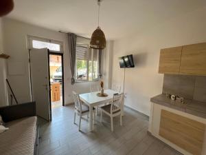 una cucina e una sala da pranzo con tavolo e sedie bianchi di Appartamento Il Garofano a Quercianella