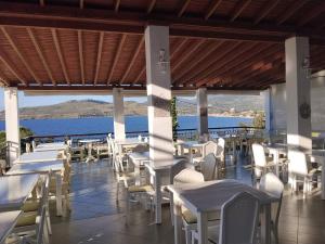 a restaurant with white tables and chairs and the ocean at Clara Resort in Petra