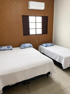 two beds in a room with a window at LD Hotel in Três Lagoas +8 photos