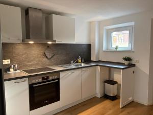 a kitchen with white cabinets and a sink and a window at VITA Apartment in Herrenberg +13 photos