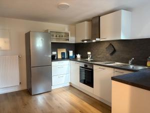 a kitchen with white cabinets and a stainless steel refrigerator at VITA Apartment in Herrenberg