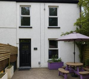 a house with a table and an umbrella in front of it at Pondside Cottage in Carmarthen