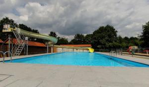 a swimming pool with a slide and a playground at de Tweelingen - de Tien Heugten in Schoonloo