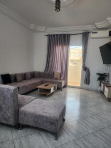 a living room with a couch and a table at Location saisonnière entre mer, forêt et calme in Raʼs al Jabal