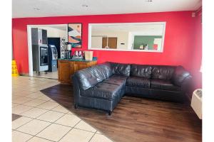 a leather couch in a living room with a red wall at Rockwood Inn Kennett I 55 Near Blytheville in Kennett