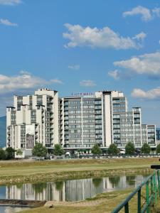 a large white building next to a body of water at Modern Riverside Apartment in Sarajevo