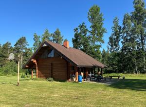 a log cabin in a field with a motorcycle parked in front at Kāpas Wood house in Uguņi +10 photos