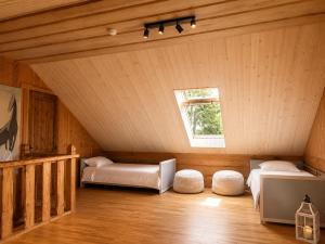 a attic room with two beds and a window at Kāpas Wood house in Uguņi