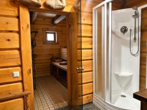 a bathroom with a walk in shower in a wooden cabin at Kāpas Wood house in Uguņi