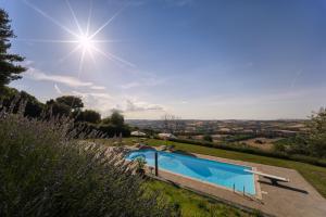 a pool in a garden with the sun in the sky at Lucciole e Lavanda BeB in Macerata