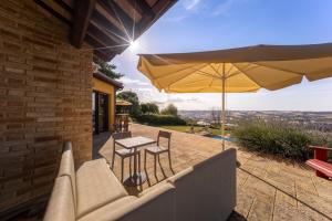a patio with a table and an umbrella at Lucciole e Lavanda BeB in Macerata