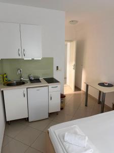 a kitchen with white cabinets and a sink and a table at Apartmani Šantić in Baška Voda